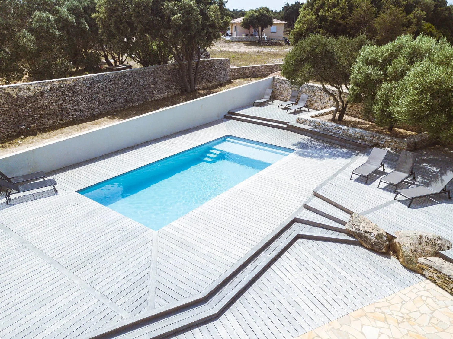 Piscine coque avec plage et environnement en pierre